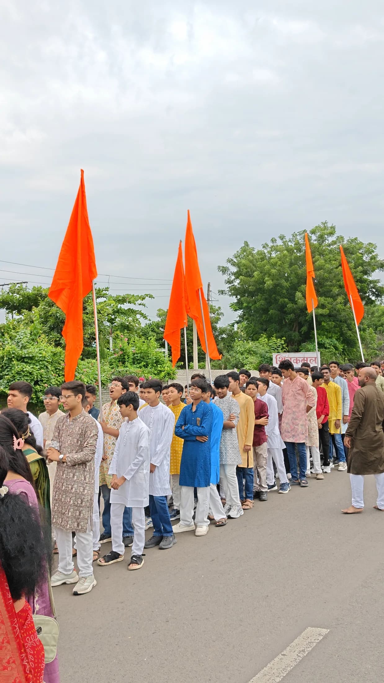Students lined up with saffron flags for the Ganpati arrival procession