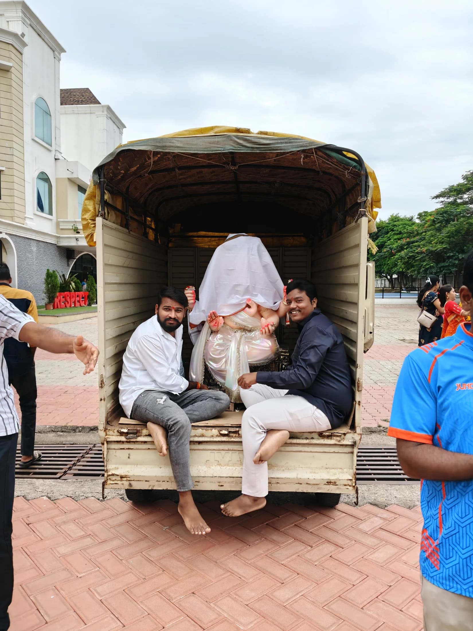 Ganpati idol being respectfully brought in under a ceremonial covering