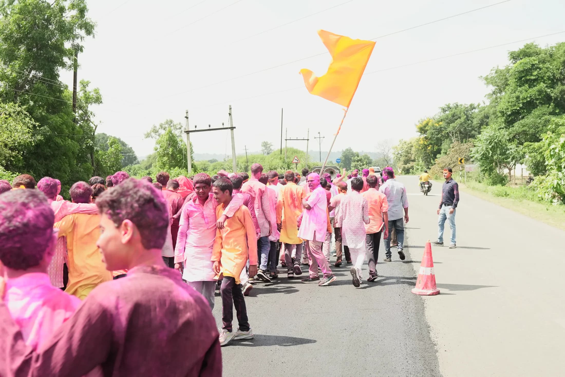 Students and community members walking in a saffron-flag Ganpati procession