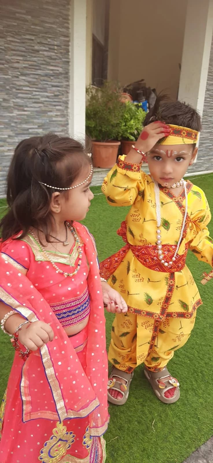 Pair of students in traditional festive Radha-Krishna costumes on the school lawn