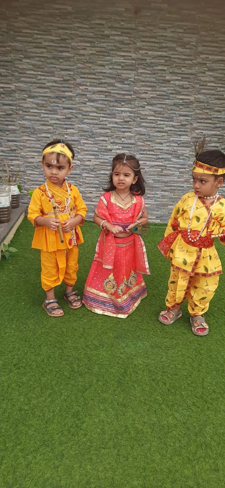 Three young learners in festive cultural attire sharing a happy moment together
