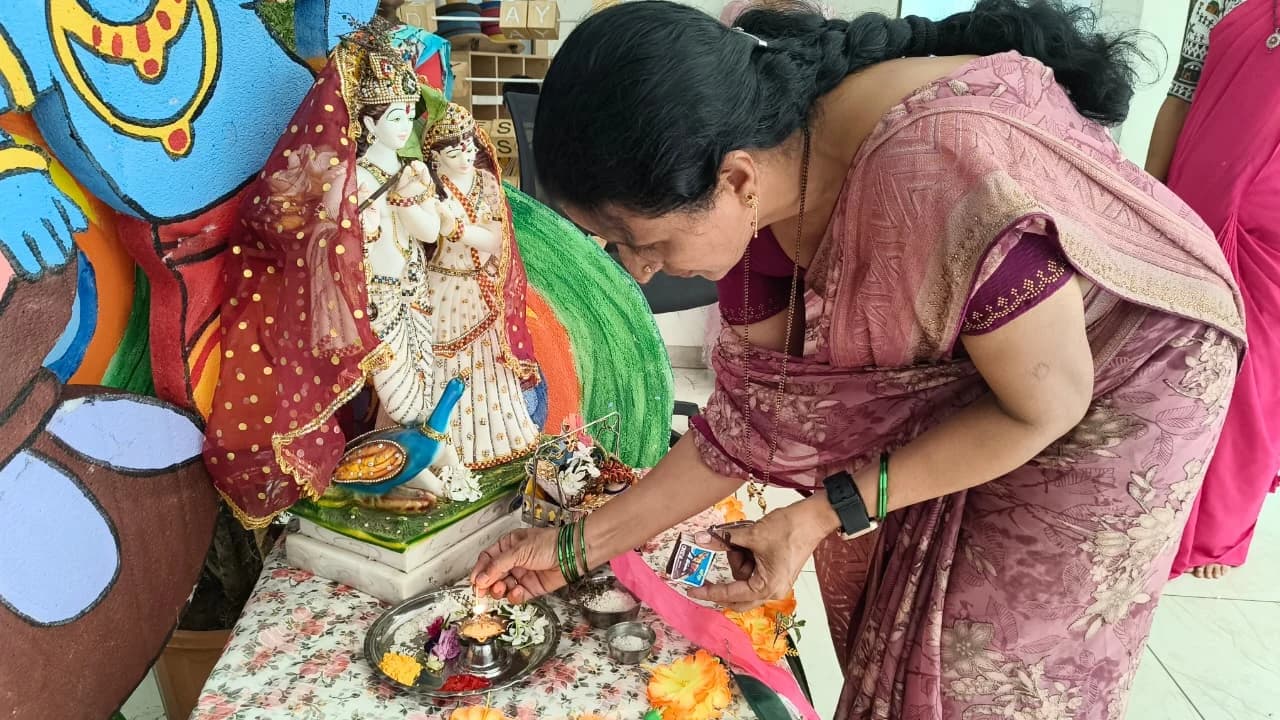 Educator lighting the prayer lamp during Janmashtami at Jet Kids